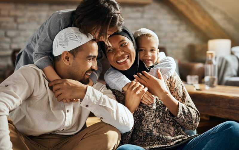 Happy Muslim parents having fun with their children who are embracing them at home.